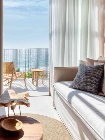 Sitzbereich mit Sofa und Meerblick durch große Fenster