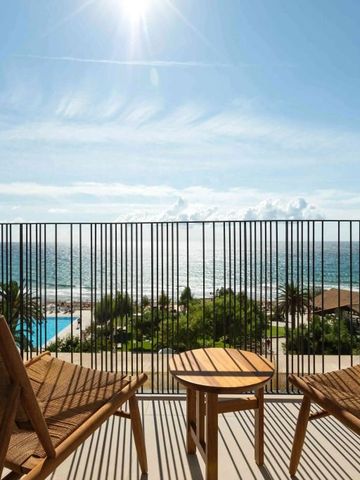 Balkon mit Sitzmöbeln und atemberaubendem Meerblick bei Sonnenschein.