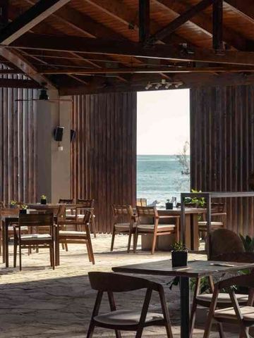Offenes Restaurant mit Holztischen und Meerblick