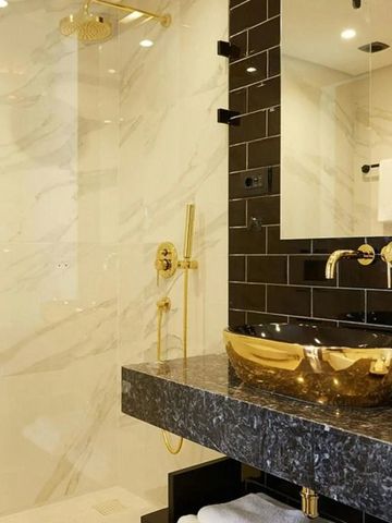 Luxuriöses Bad mit goldenen Armaturen und Glaselementen
