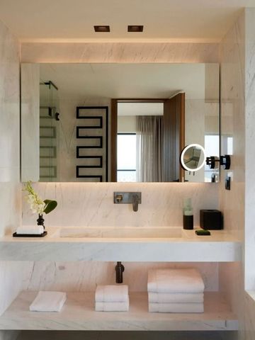 Badezimmer mit großzügigem Spiegel und eleganten Marmoroberflächen