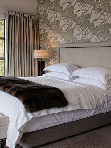 Gemütliches Schlafzimmer mit großem Bett und floralem Muster an der Wand