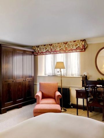 Elegantes Hotelzimmer mit Sitzgelegenheit und Holzschrank