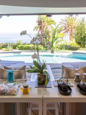 Luxuriöse Terrasse mit Meerblick und Pool, umgeben von tropischen Pflanzen
