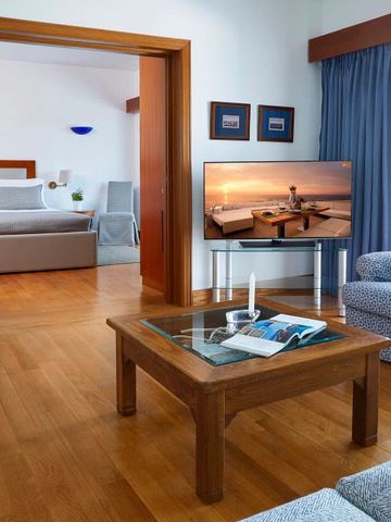 Suite mit getrenntem Schlaf- und Wohnbereich, Holzfußboden, Fernseher.