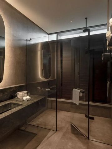 Dunkles modernes Badezimmer mit Glasdusche und stilvollem Waschbecken.