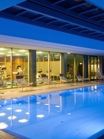 Beleuchteter Innenpool mit angrenzendem Fitnessbereich im Hotel