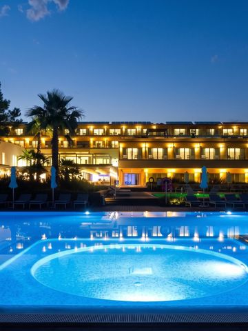 Beleuchtete Hotelansicht bei Nacht mit Pool im Vordergrund