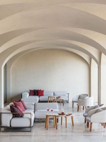 Elegante Lounge mit weißem Sofa und stilvollen Kissen unter gewölbter Decke