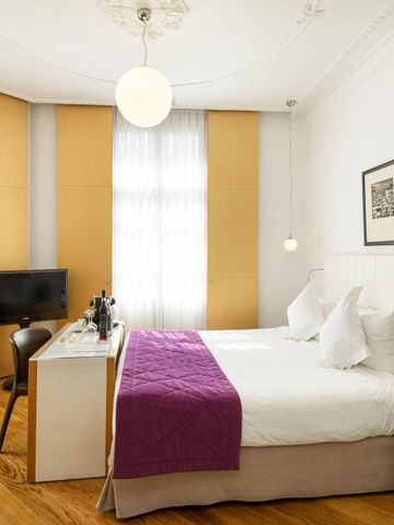 Gemütliches Hotelzimmer mit hellen Vorhängen und lila Farbgebung