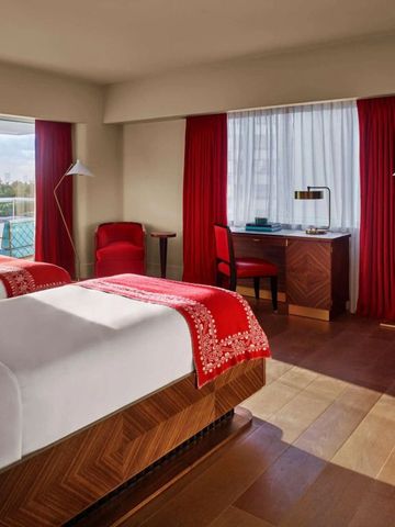 Doppelzimmer mit Holzböden, roten Vorhängen und Balkon mit Ausblick