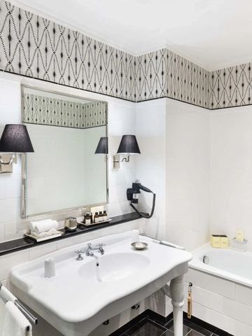 Elegantes Badezimmer mit großzügigem Spiegel und stilvollen Lampen.
