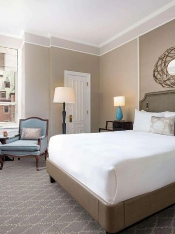 Geräumiges Schlafzimmer mit großem Bett und Blick auf die Architektur des Chateau Frontenac.