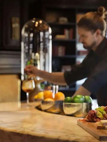 Barkeeper an einer stilvollen Bar mit Getränken und Früchten