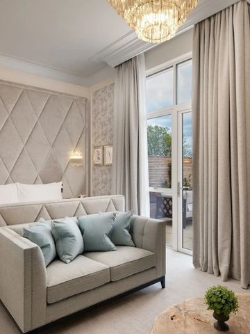 Elegantes Zimmer mit Sofa vor einem Bett und opulentem Kronleuchter
