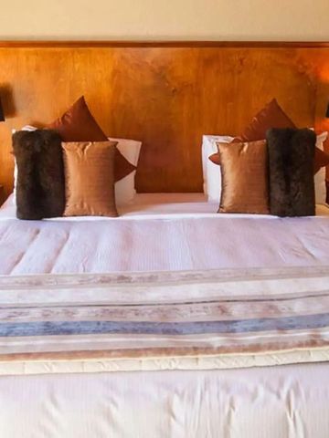 Luxuriöses Bett mit eleganten Kopfkissen und Holzdekor im Hotelzimmer