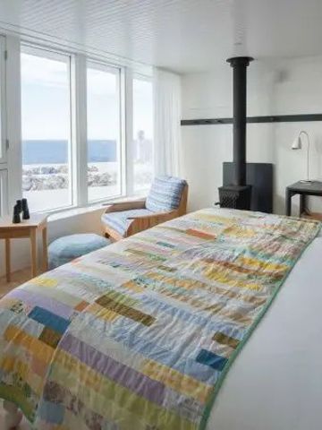 Helles Zimmer mit großem Fenster und Meerblick. Ein Kamin sorgt für Gemütlichkeit