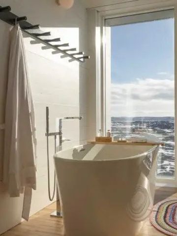 Freistehende Badewanne mit Blick auf eine offene winterliche Landschaft