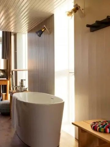 Freistehende Badewanne in einem stilvoll eingerichteten Zimmer mit Holzwänden und Dekoration.