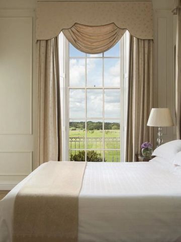 Elegantes Schlafzimmer mit großem Fenster und Blick auf die grüne Umgebung