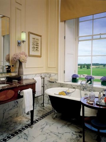 Elegantes Badezimmer mit freistehender Badewanne und Blick auf die Landschaft.
