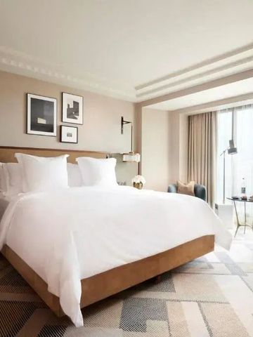 Luxuriöses Hotelzimmer mit Kingsize-Bett und großen Fenstern.