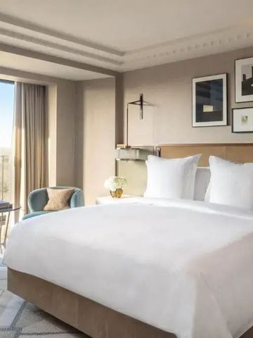 Helles Hotelzimmer mit Kingsize-Bett und Fensterausblick.