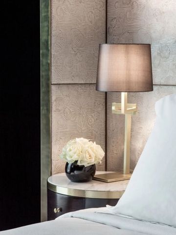 Elegantes Schlafzimmer mit stilvoller Beleuchtung und Blumen auf dem Nachttisch