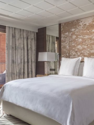 Luxuriöses Doppelzimmer mit großem Bett und Balkonblick in den Bergen.