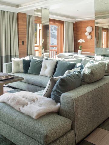 Gemütliche Lounge mit großen Sofas und vielen Kissen in einem eleganten Chalet.