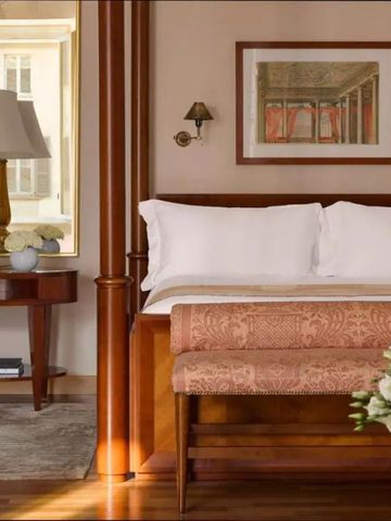 Elegantes Hotelzimmer mit Holz- und Beigetönen, Kingsize-Bett und kunstvoll eingerichteter Ecke