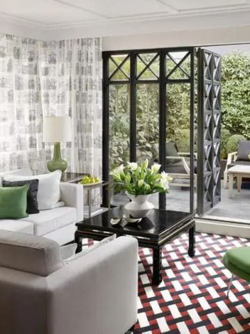 Chic eingerichtetes Wohnzimmer mit geometrischem Teppich und Zugang zu begrüntem Balkon