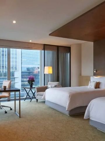 Helles Zimmer mit zwei Betten und Aussicht auf moderne Architektur.