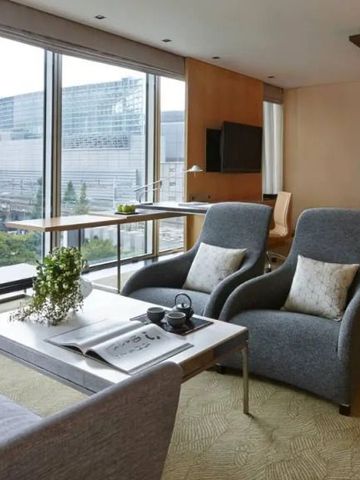 Geräumige Hotelsuite mit modernen Sesseln und Panoramablick auf die Stadt.