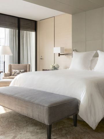 Helles und gemütliches Schlafzimmer mit weißer Bettwäsche und Sitzbereich.