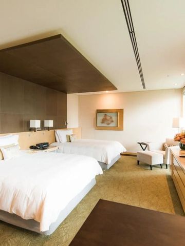 Helles Hotelzimmer mit zwei Doppelbetten und einem großen Fernseher