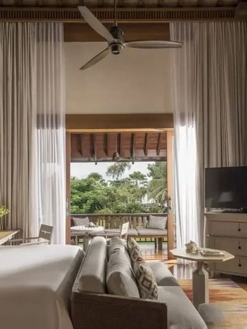 Luxuriöses Schlafzimmer mit Baldachin und Blick auf üppige Natur durch offene Türen