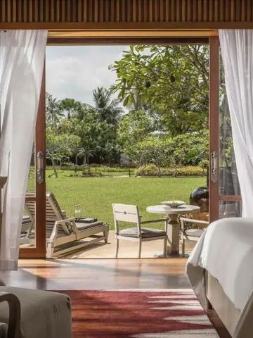 Helles Zimmer mit Blick auf Garten und Liegestühle durch eine große Glasschiebetür