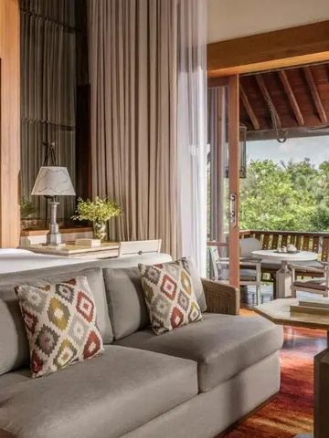 Gemütliches Schlafzimmer mit Sofa und Balkon mit Blick auf tropische Vegetation