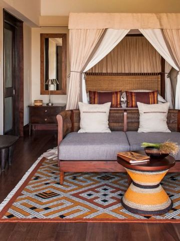 Luxuriöses Zimmer mit afrikanischen Akzenten und gemütlicher Sitzecke im Four Seasons Safari Lodge.