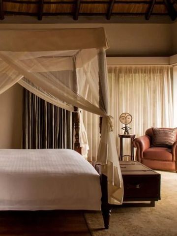 Schlafzimmer mit Himmelbett und warmem, afrikanischem Ambiente