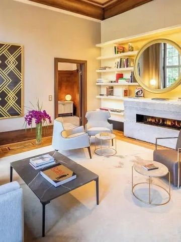 Luxuriöse Lounge mit Kamin, stilvollen Möbeln und Regalen im Fraser Suites Hamburg