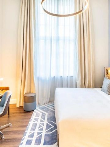 Modernes Hotelzimmer mit großem Fenster, Schreibtisch und gemütlichem Bett.