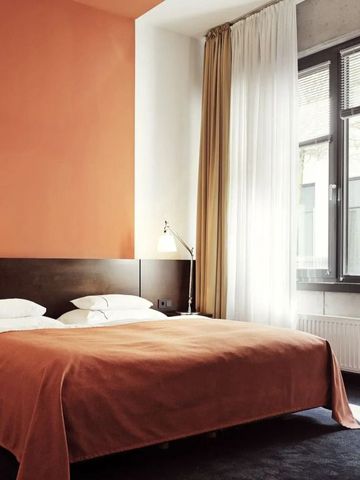 Modernes Hotelzimmer mit oranger Wand und großem Fenster