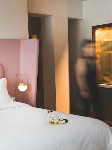 Gemütliches Hotelzimmer mit rosa Kopfteil und eleganter Einrichtung.