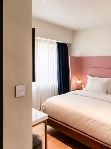 Elegantes Hotelzimmer mit großem Bett und rosa Kopfteil