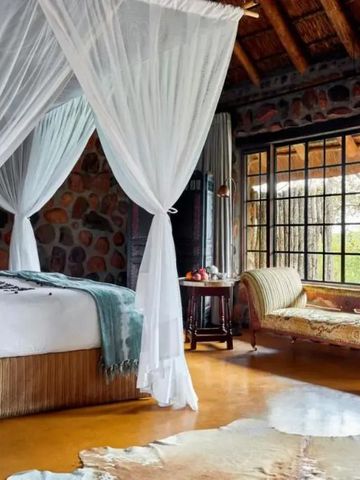 Schlafzimmer im Lodge-Stil mit großen Fenstern und Baldachinbett