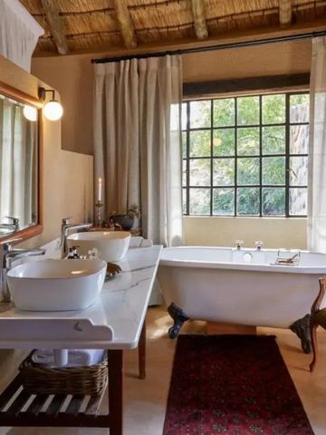 Geräumiges, rustikales Badezimmer mit großer Badewanne und Fenstern