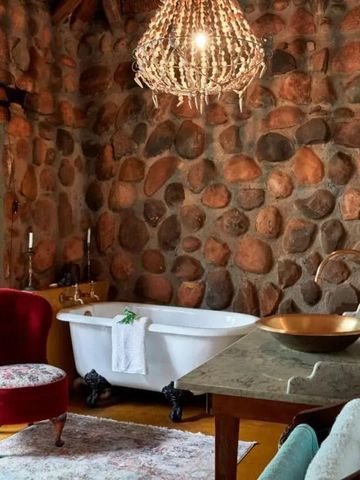 Charmantes Badezimmer mit freistehender Badewanne und rustikaler Steinwand