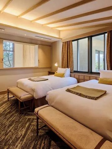 Modernes Hotelzimmer mit zwei gemütlichen Einzelbetten und großen Fenstern